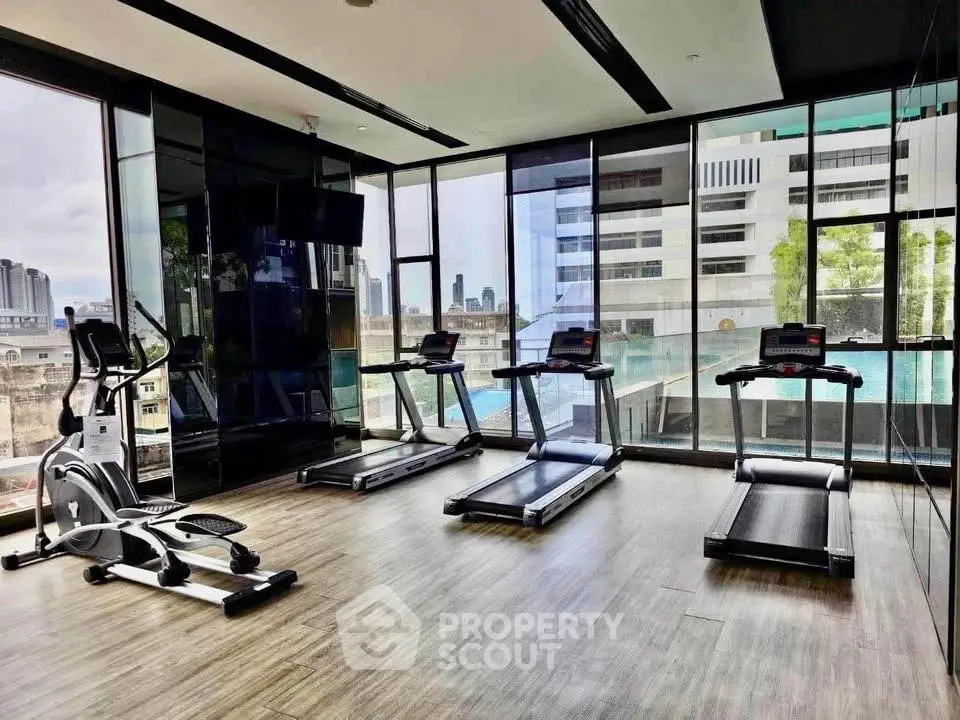 Modern gym with treadmills and city view in luxury apartment building.