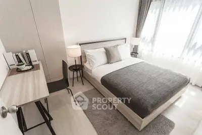 Modern bedroom with stylish decor and natural light, featuring a cozy bed and elegant furnishings.