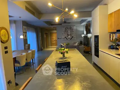 Spacious modern kitchen with open layout and stylish dining area, featuring contemporary lighting and decor.