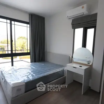 Modern bedroom with large window and air conditioning unit, featuring a sleek bed and vanity.