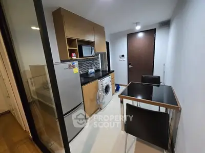 Modern compact kitchen with dining area, featuring fridge, washing machine, and sleek cabinetry.