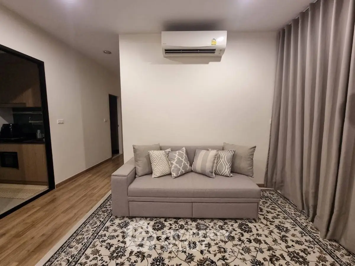 Modern living room with stylish sofa and air conditioning, featuring elegant decor and cozy ambiance.