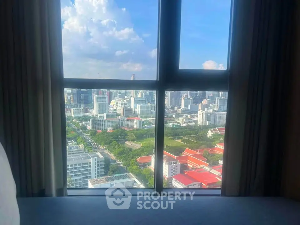 Stunning cityscape view from a high-rise apartment window, showcasing urban skyline and lush greenery.