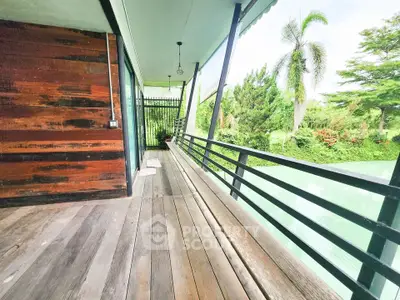 Charming wooden balcony with lush garden view, perfect for relaxation and outdoor enjoyment.