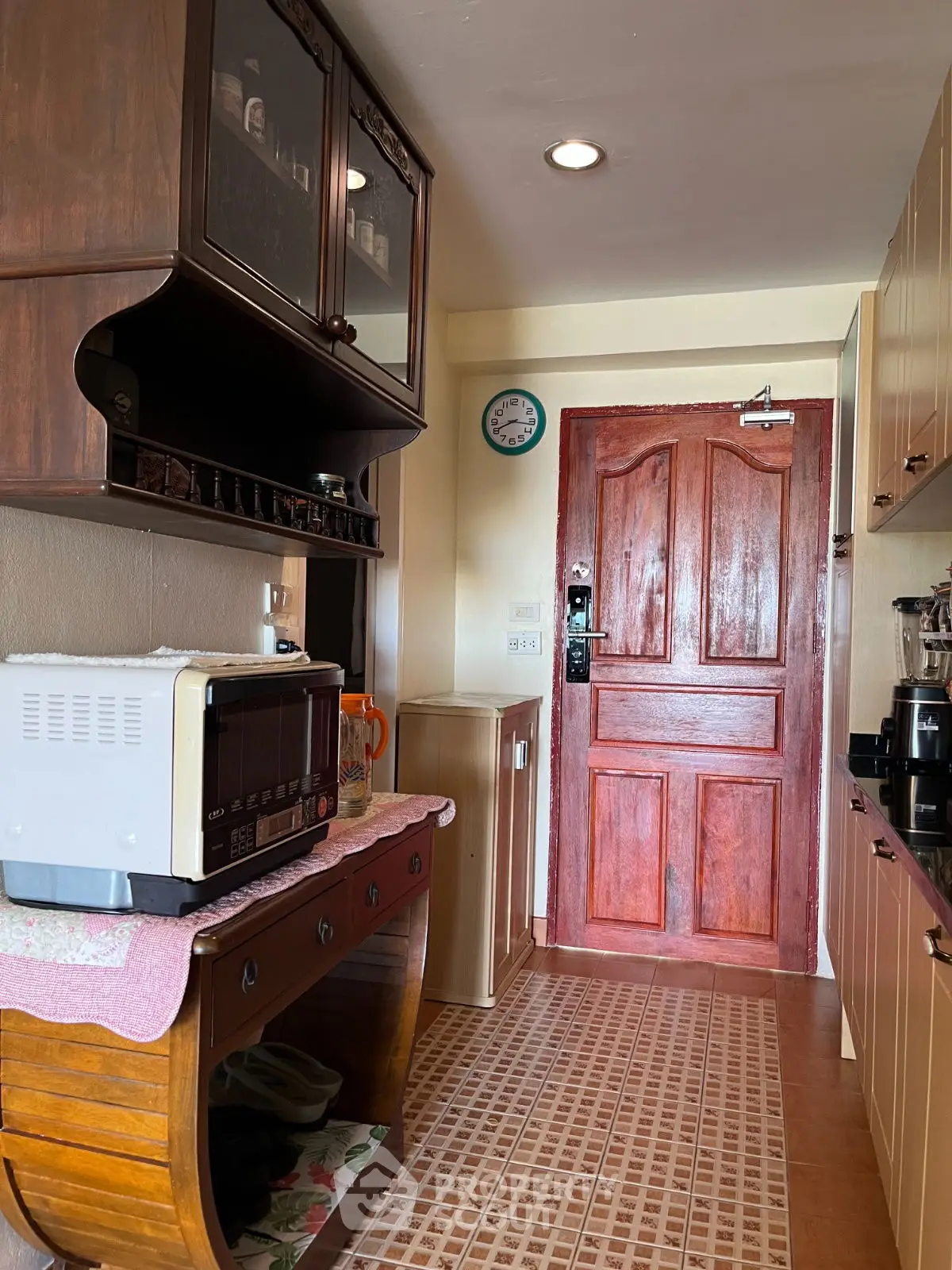 Charming kitchen with wooden cabinets and modern appliances, featuring a warm wooden door and tiled floor.