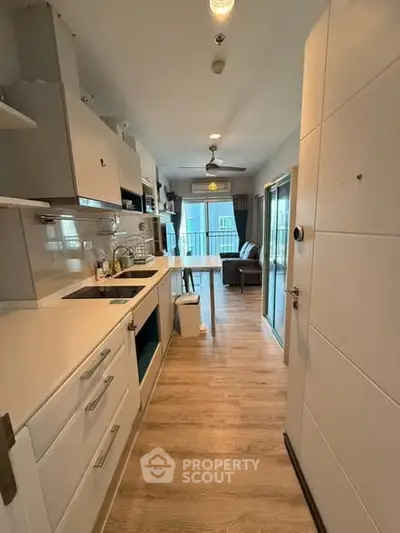 Modern kitchen with open layout and sleek design, featuring wooden flooring and ample natural light.