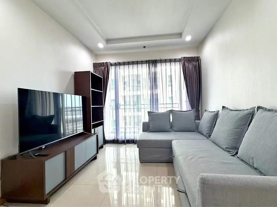 Spacious modern living room with large TV and comfortable gray sofa, perfect for relaxation.