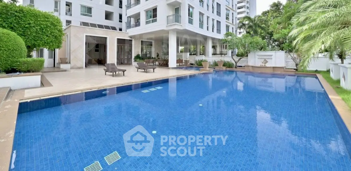 Luxurious residential building with spacious outdoor pool and lush greenery.