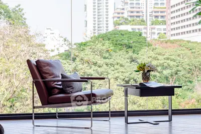 Modern living room with stylish chair and table, featuring a stunning cityscape view through large windows.