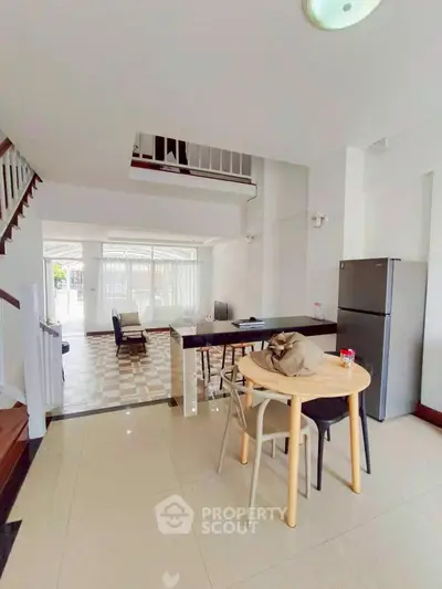 Spacious open-plan living area with modern kitchen and dining space, featuring natural light and stylish decor.