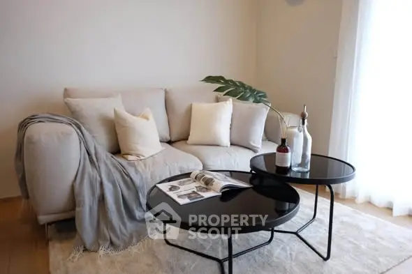 Stylish living room with cozy beige sofa and modern black coffee tables.
