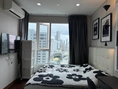 Modern bedroom with city view, featuring stylish decor and large window for natural light.