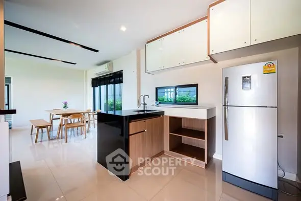 Modern kitchen with sleek design and open dining area, featuring a large fridge and ample natural light.