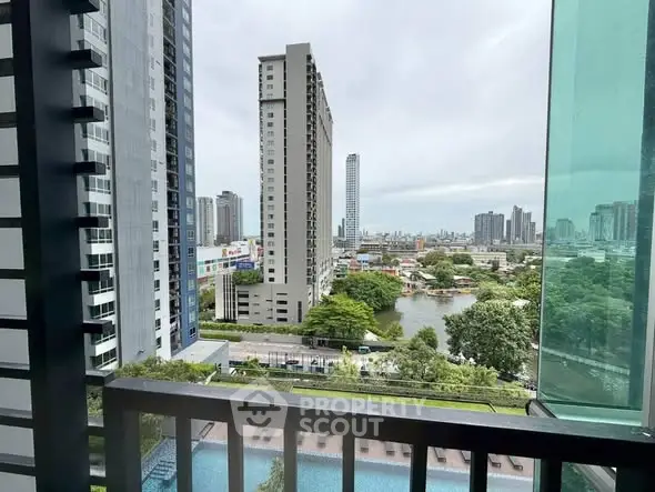 Stunning cityscape view from a high-rise balcony overlooking a serene pool and lush greenery.