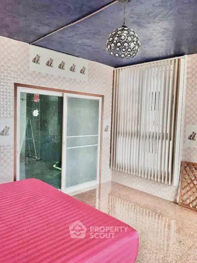 Unique bedroom with modern decor and sliding glass doors, featuring a vibrant pink bedspread and stylish lighting.