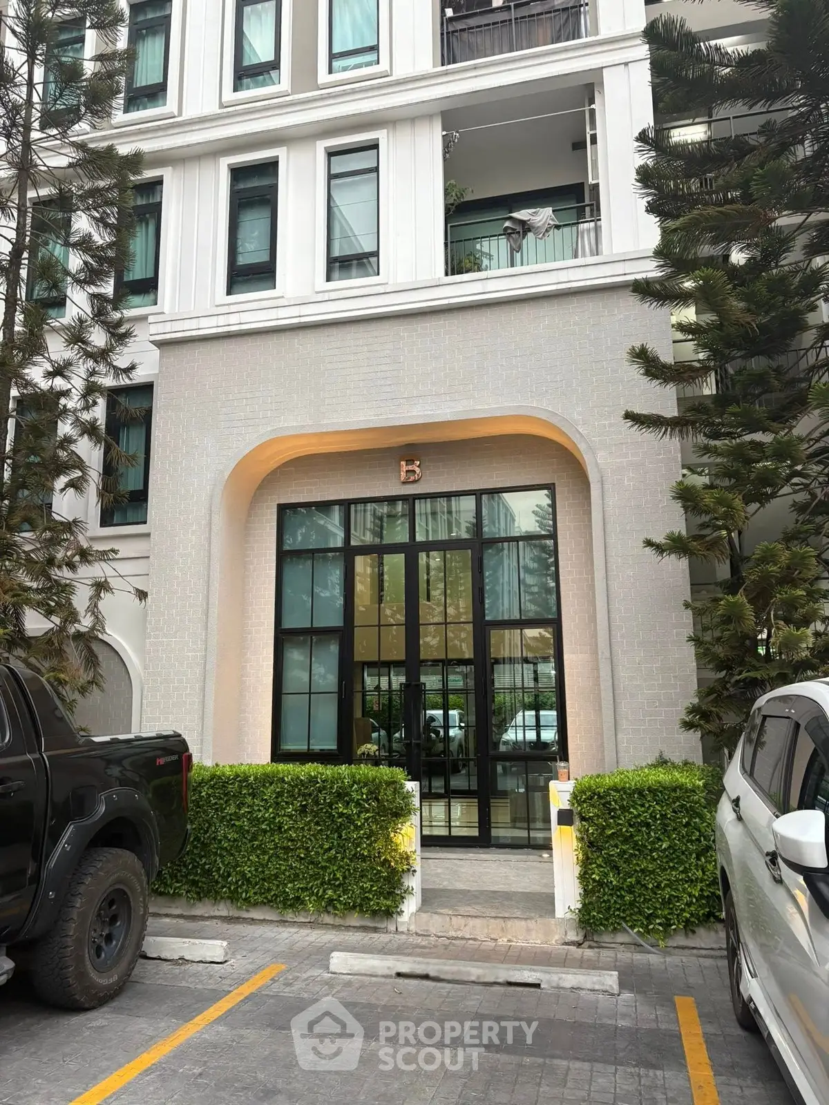 Elegant building entrance with modern design and lush greenery, perfect for urban living.