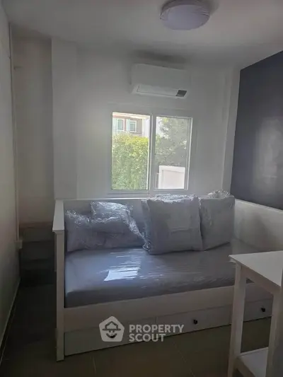 Cozy bedroom with natural light and modern air conditioning unit, perfect for relaxation.