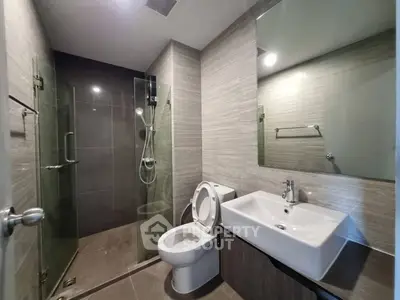 Modern bathroom with glass shower and sleek fixtures in contemporary apartment.