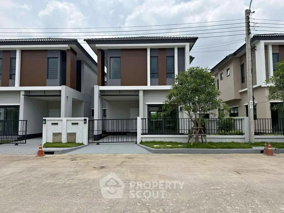 Modern two-story house with sleek design and spacious driveway in a suburban neighborhood.