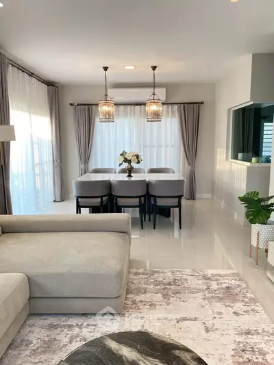 Elegant living room with modern dining area, featuring stylish lighting and a cozy sofa, perfect for family gatherings.