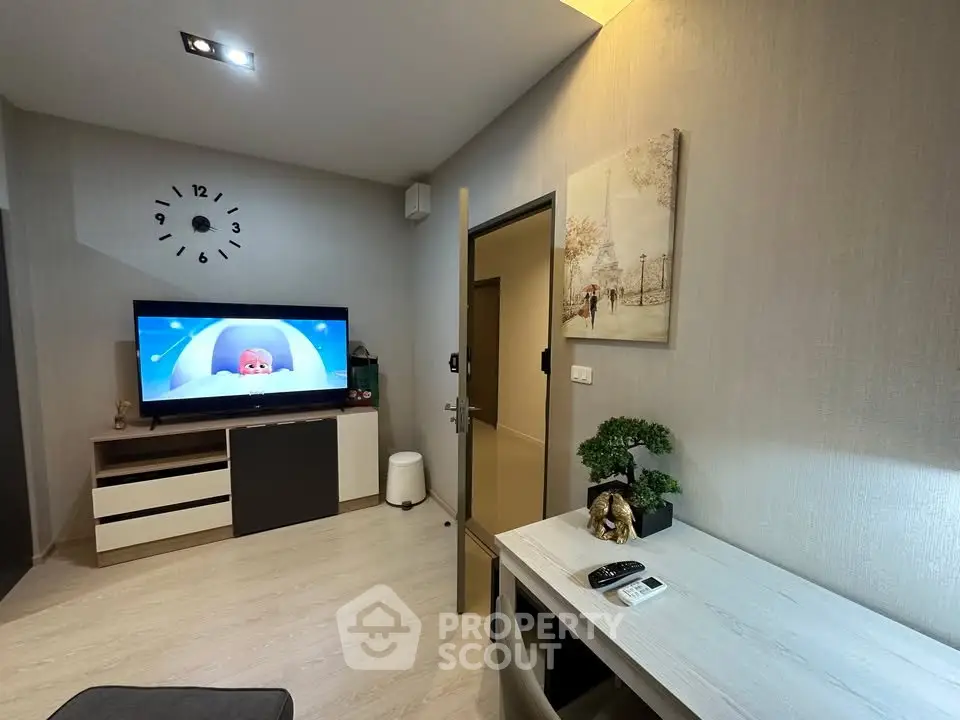 Modern living room with stylish decor and wall-mounted TV, featuring a cozy workspace and elegant wall art.