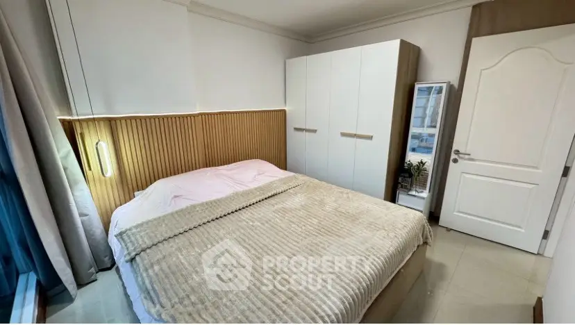Cozy bedroom with modern decor and ample natural light, featuring a stylish wardrobe and elegant bedding.
