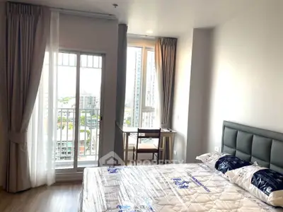 Bright bedroom with large windows and city view, featuring a cozy bed and a small desk.