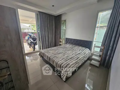 Spacious bedroom with modern decor and outdoor access, featuring a comfortable bed and natural light.