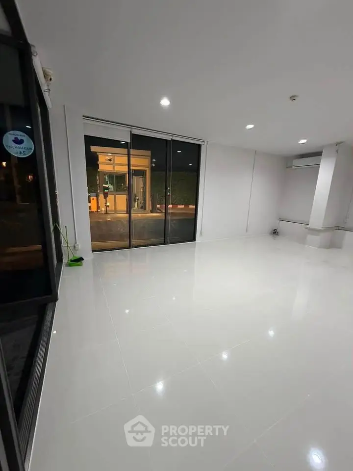 Spacious modern living room with large windows and sleek white flooring.