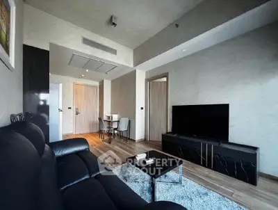 Modern living room with sleek black furniture and wooden flooring