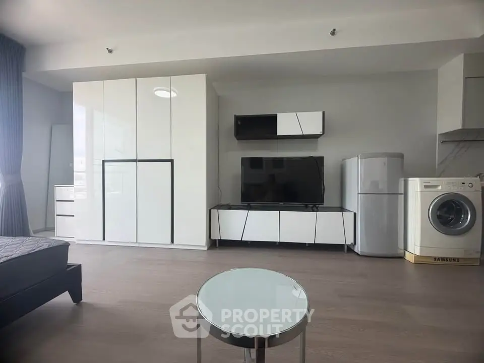 Modern living room with sleek furniture and appliances, featuring a washing machine and refrigerator.