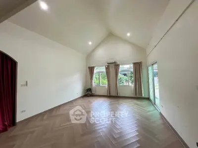 Spacious empty living room with large windows and herringbone wood flooring