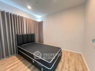 Spacious bedroom with modern design and wooden flooring, featuring a large bed and elegant curtains.