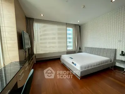 Spacious modern bedroom with large window and sleek furnishings in urban apartment.