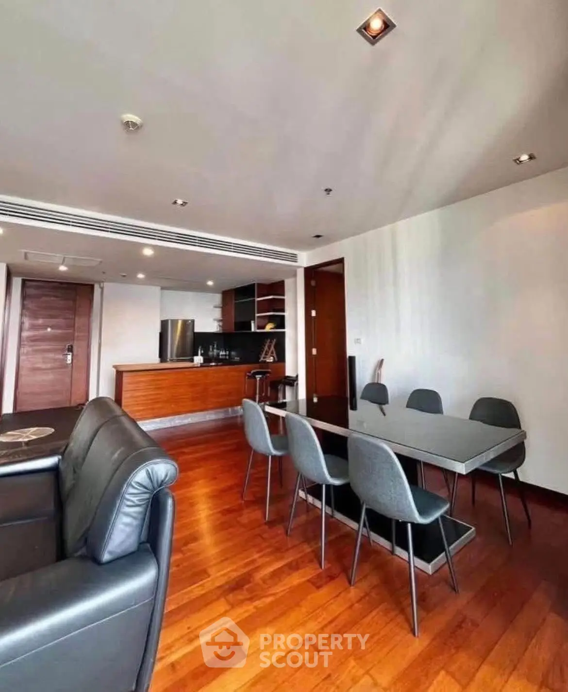Spacious modern living room with open kitchen and elegant dining area, featuring sleek furniture and wooden flooring.