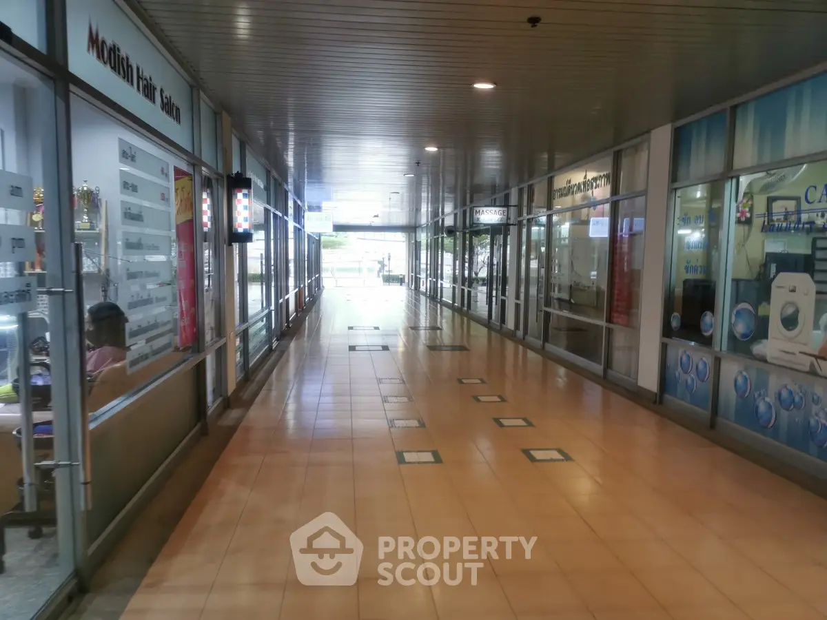 Spacious commercial corridor with glass storefronts and tiled flooring