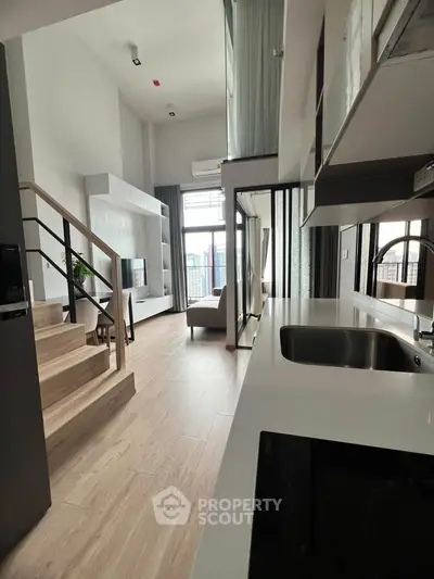 Modern loft apartment with open kitchen and stylish living area, featuring high ceilings and large windows.