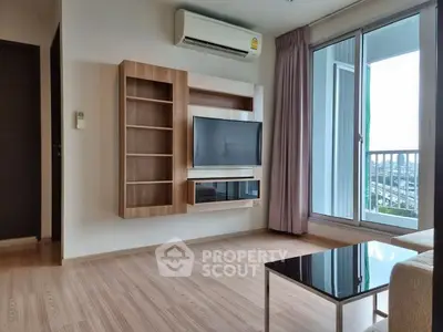 Modern living room with sleek TV setup and balcony view in a stylish apartment.