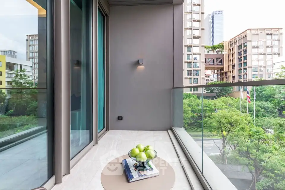 Modern balcony with glass railing and city view, featuring a small table with green apples.