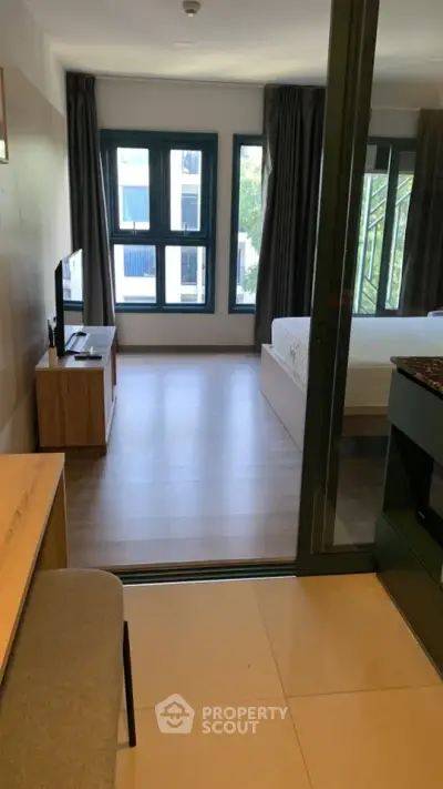 Modern studio apartment with open layout and large windows offering natural light.