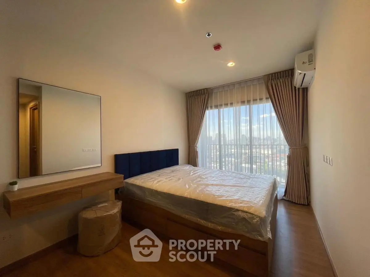 Modern bedroom with large window and city view, featuring stylish decor and natural light.