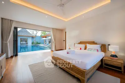 Luxurious bedroom with pool view in modern villa, featuring elegant wooden furniture and ambient lighting.