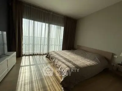 Spacious bedroom with large windows and natural light in modern apartment.