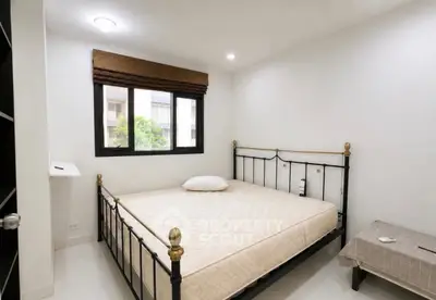 Cozy bedroom with large window and stylish metal bed frame in modern apartment.