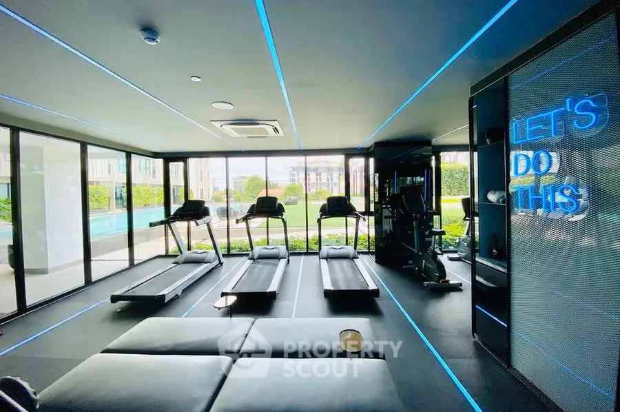 Modern gym with treadmills and motivational neon sign in luxury apartment complex.
