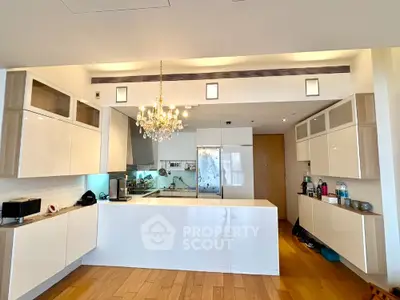 Luxurious modern kitchen with sleek white cabinetry and elegant chandelier lighting