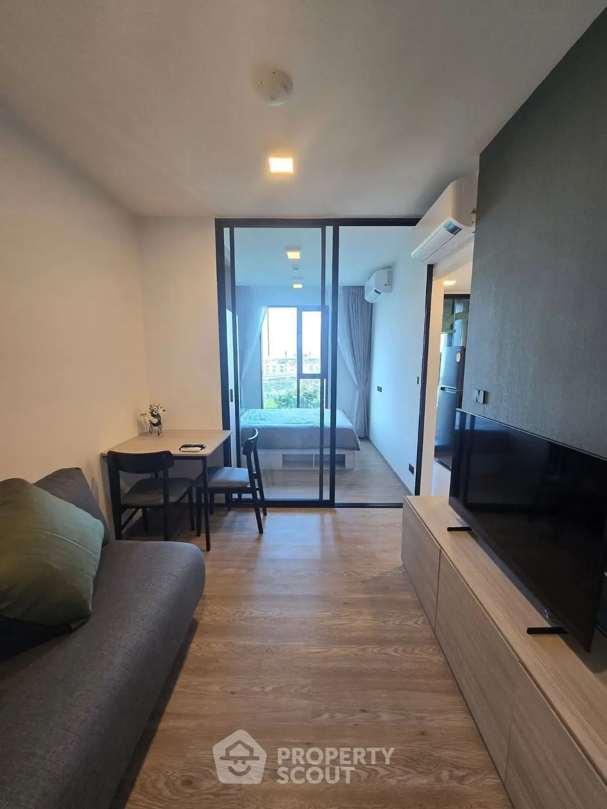 Modern apartment interior with cozy living room and bedroom separated by glass doors, featuring stylish decor.