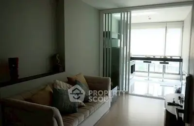 Modern living room with cozy sofa and sliding glass doors leading to a bright dining area.