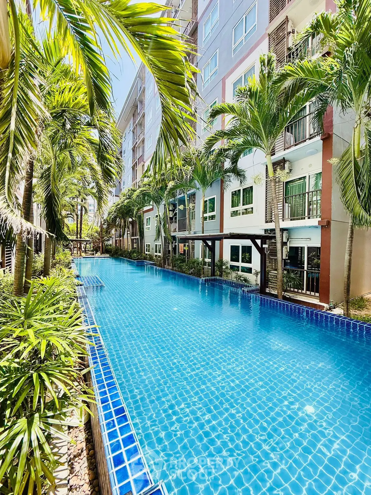 Luxurious condominium with stunning pool and lush palm trees, perfect for resort-style living.