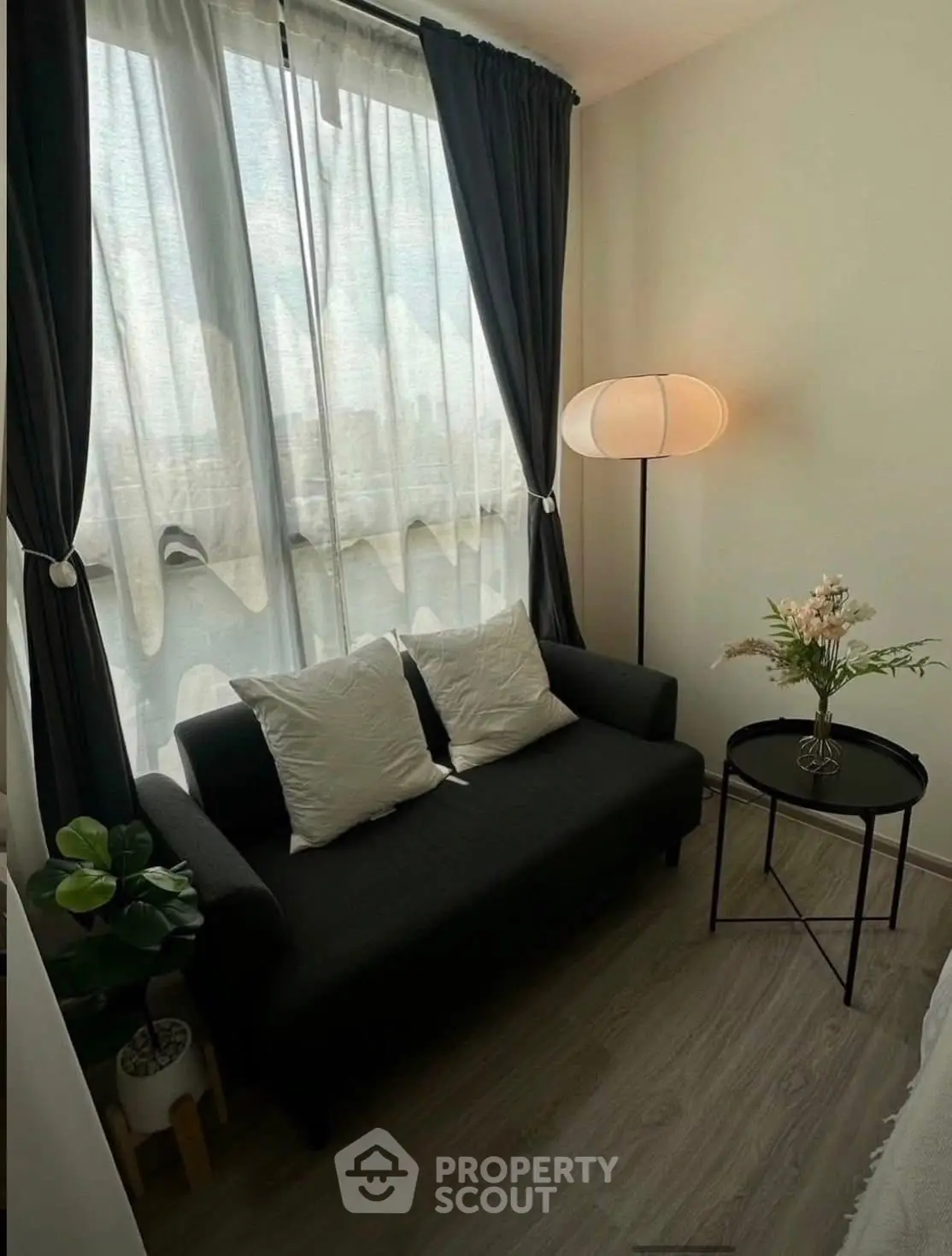 Cozy living room with modern sofa, elegant lamp, and natural light through large window.